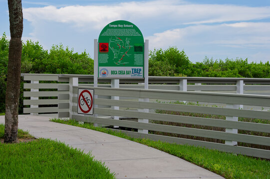 Green interpretive sign for the Tampa Bay Estuary and Boca Ciega Bay sits on a boardwalk overlooking coastal vegetation. Editorial Use Only, September 23,  2026 ,South Pasadena, FL ,USA, promoting sea