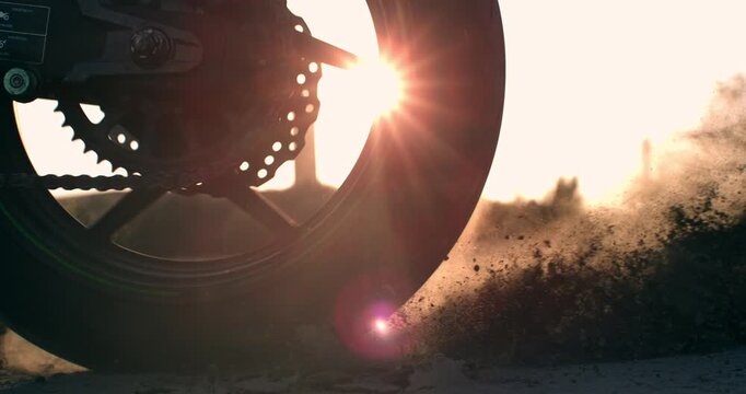 Extreme close-up of a sport motorcycle tire spinning and skidding across sandy desert terrain at 1000 fps, kicking up dust in a powerful cinematic slow-motion action shot.