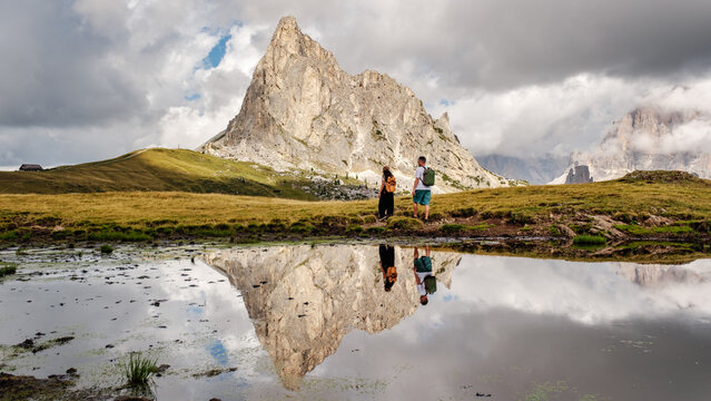 Majestic mountain peaks rise above lush green meadows at Passo Giau, Dolomites, Italy. Visitors enjoy the breathtaking scenery, surrounded by natures beauty. Perfect for a tranquil getaway.