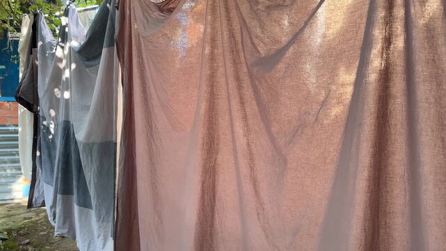 Freshly washed duvet cover and sheet drying outdoors, camera moves closer
