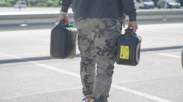 Person carry two gasoline containers to the vehicle