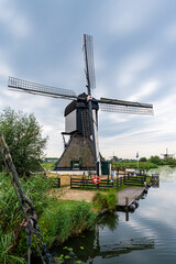 Fototapeta premium Renovated windmill at a river bank in Kinderdijk