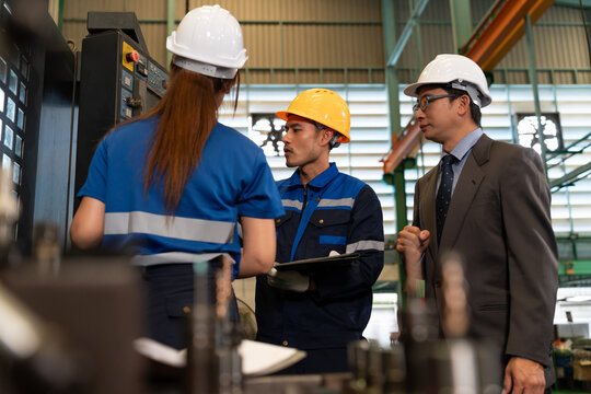 Industrial workers, engineers, and a supervisor collaborate beside factory machinery, discussing technical work while representing teamwork, safety, engineering, inspection, and manufacturing.