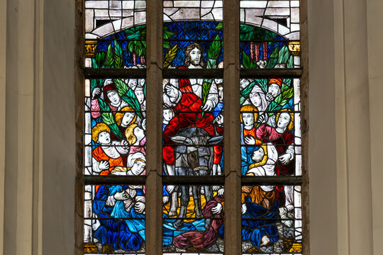Close-up on religious stained-glass decoration showing Jesus surrounded by people at Palm Sunday