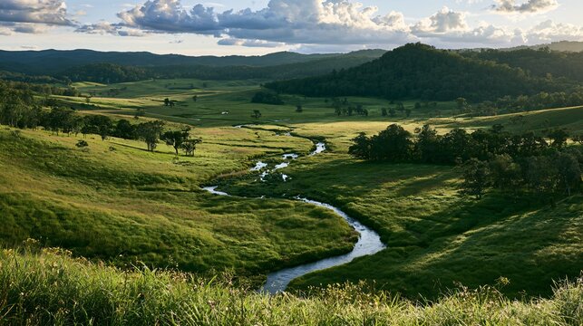 Wide establishing shot of a lush green valley with a winding river cutting through tall grass and