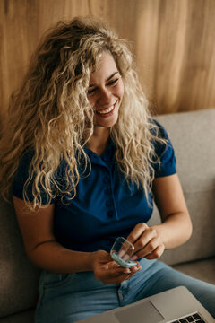 Happy woman holding hearing device case by laptop