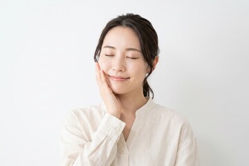 Fototapeta premium 潤いのある肌に触れて微笑む女性（美肌・基礎化粧品・エイジングケア・余白）