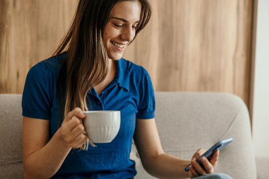 Woman smiling, relaxing with coffee and smartphone