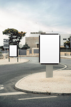 Blank vertical billboard mockup on a curved urban roadside, with a second empty display behind it and generous white space ready for advertising, branding or directions