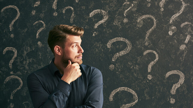 A thoughtful man stands in front of a wall adorned with question marks, deep in contemplation, symbolizing curiosity and uncertainty in decision-making.