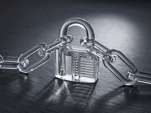 Transparent padlock and chain on dark surface representing security