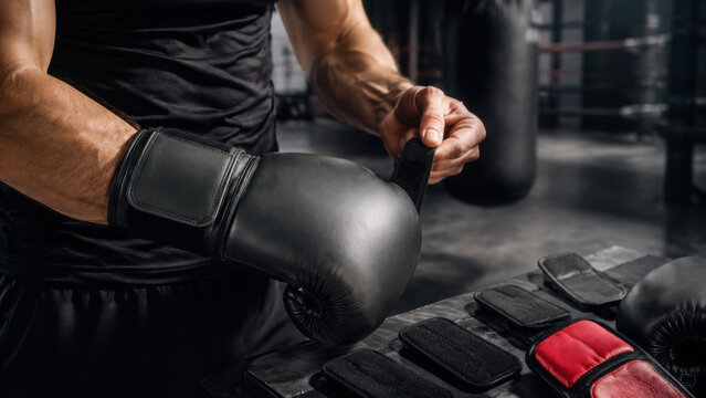 Customizable sports gear for boxing training with black glove, hand wrap, and red protective equipment in dark gym setting