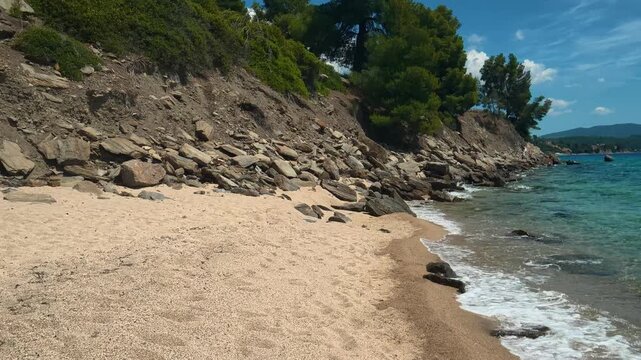 Sunlit beach meets turquoise sea, gentle waves roll in. Lagomandra, Greece