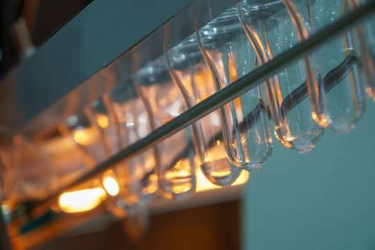 Close up of plastic bottle preforms on a conveyor belt moving to a blow molding machine