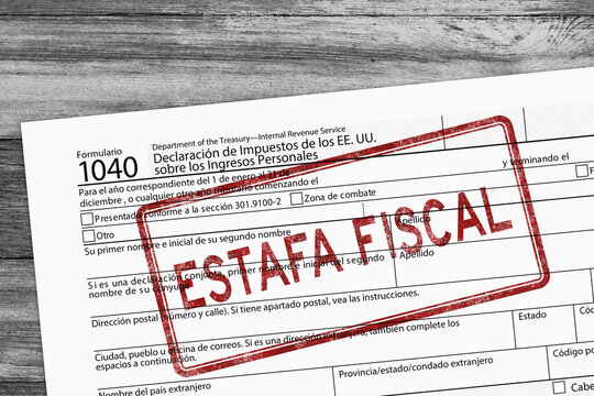 1040 tax return form in Spanish with red distressed Estafa Fiscal in Spanish Tax Scam  stamp  on wood