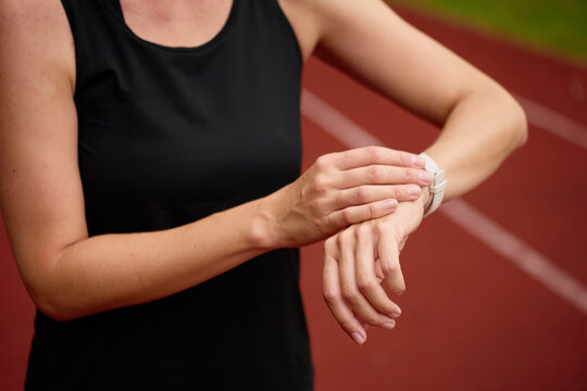 Woman checking fitness watch during workout on stadium running track