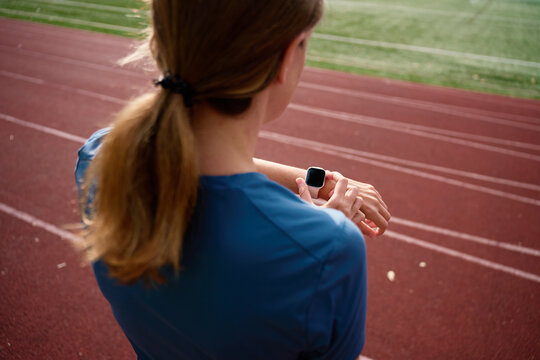 Woman checking smartwatch during workout on running track