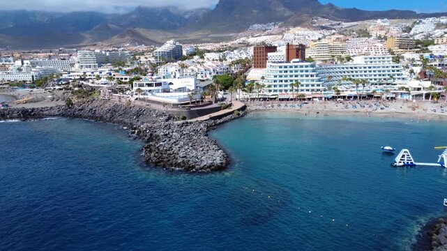Dron revela una playa resguardada con parque acu&aacute;tico hinchable flotante, hoteles y monta&ntilde;as al fondo, Costa Adeje, Tenerife, Islas Canarias