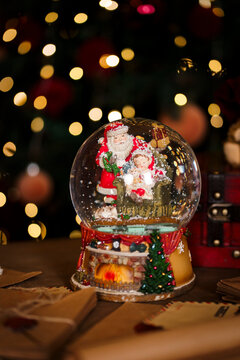 Festive decor with red vintage chest soft toy bear and musical snow globe near Christmas tree