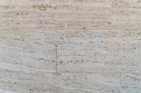 Light travertine tile wall showing subtle veins in pale stone
