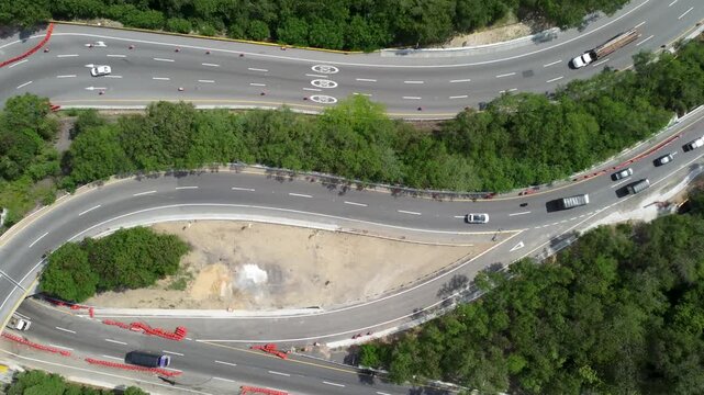 Top view drone road in construcction in middle of mountains, curved road cars traveling trees and grass, Colombia 4k