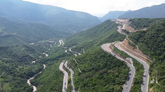Aerial view drone road in construcction in middle of mountains, curved road cars traveling trees and grass, Colombia 4k