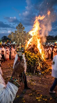 Holding traditional brass cross during meskel holiday celebration, orthodox ethiopian religious ceremony with burning bonfire, yellow flower decoration, praying believer crowd at dusk.