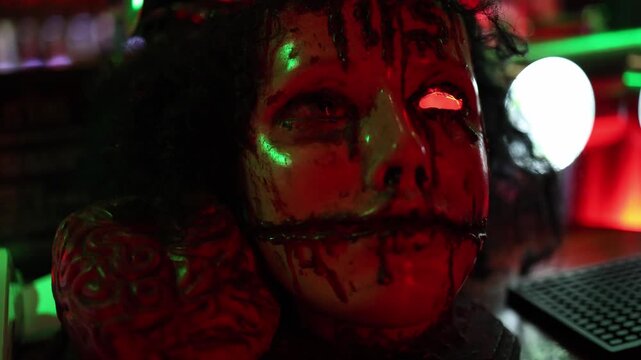 Halloween horror mannequin with damaged face stitched mouth and exposed brain creates a disturbing nightmare scene under intense red and green lights in a dark room