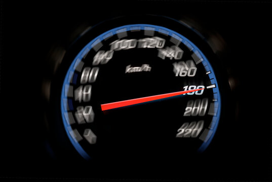 A glowing car speedometer displays a high speed against a dark background.