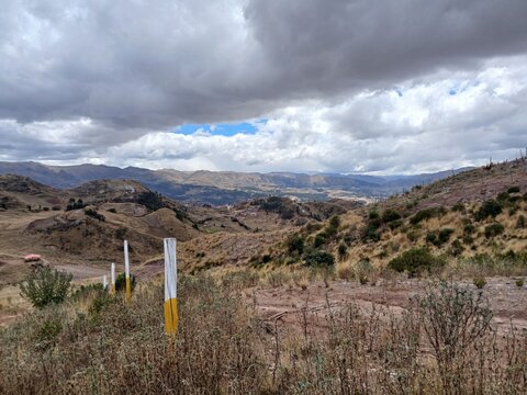 View of mountains and a path with a cloudy sky in the background in Cusco, Peru.