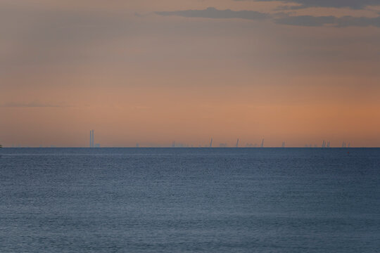 Langrune-Sur-Mer, France - 08 09 2026: Sunrise over the sea from the beach and the port of Le Havre far away
