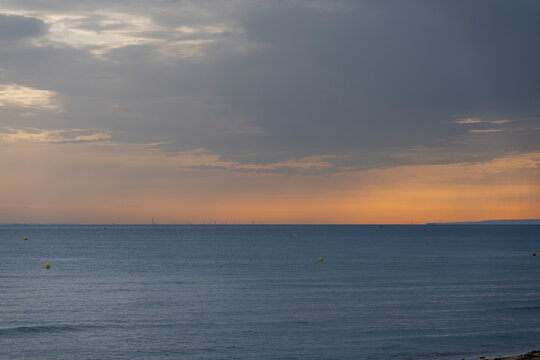 Langrune-Sur-Mer, France - 08 09 2026: Sunrise over the sea from the beach and the port of Le Havre far away