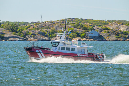 Gothenburg, Sweden - August 11 2026: Fast workboat creating spray beside rocky Swedish coast.