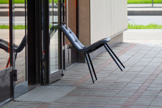 Black modern chair wedged against glass entrance door to keep it open