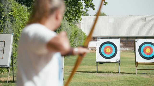Focused mature man shooting an arrow at a target during an archery competition. Outdoor recreational activity and sporting lifestyle