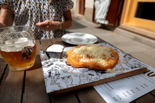 Krakow, Poland - July 18, 2026: Langos the popular Hungarian open-faced pastry served with beer at an outdoor table in Kazimierz.