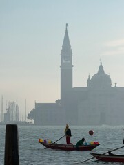 Misty Venice lagoon with Basilica of San Giorgio Maggiore in the background and a traditional Venetian boat on the water, creating an atmospheric Italian travel scene © Polina
