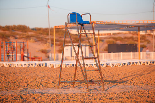 Lifeguard tower with a blue seat, situated amidst the sea and sands.