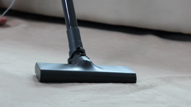 Powerful modern vacuum cleaner nozzle brushing and cleaning a dirty shaggy carpet in a living room, highlighting routine housekeeping and domestic hygiene concepts