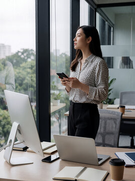 Thoughtful Businesswoman Looking Out Window in a Modern Office