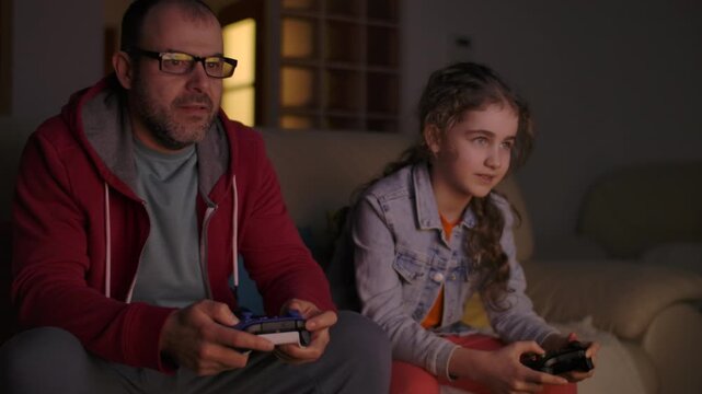 Father and Daughter Expressing Emotions While Enjoying Relaxing Together, Playing Video Games in Front of TV.  Family Time Hobby. Family Having Fun Together at Home in Living Room Playing Video Games.