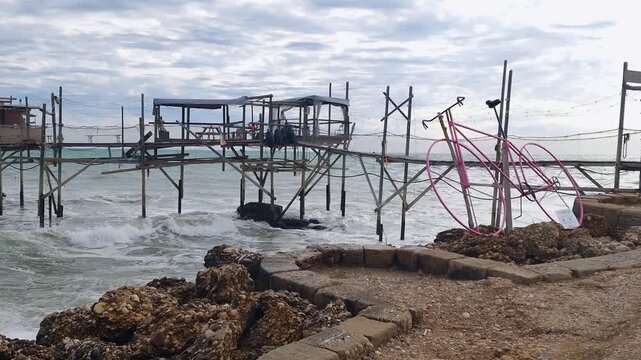 Trabocco Costa dei Trabocchi Abruzzo Italy. view with pink bicycle cycle path via verde seaside bike trail panning shot dramatic sky waves sound ambient 4k video
