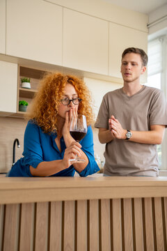 Couple fighting in the kitchen with a glass of red wine on the counter