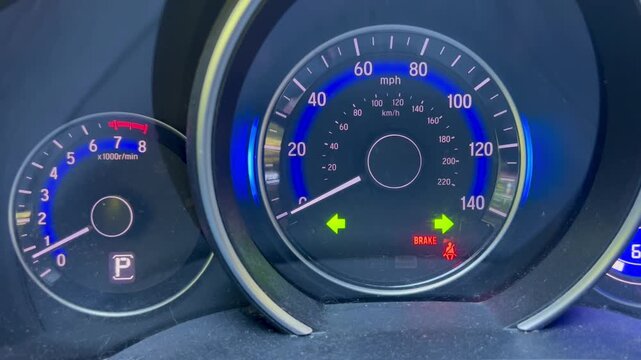 Hazard lights flashing on car dashboard speedometer close up