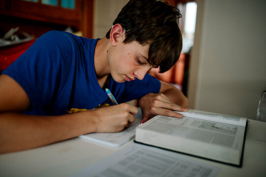 Teen Student with Cochlear Implant Studying and Writing at Home