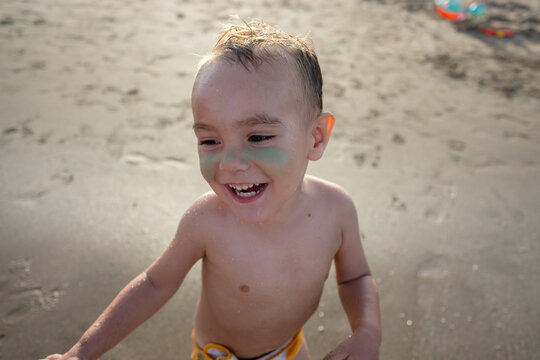 toddler boy laughing playing at beach