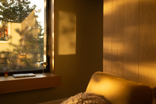 Sunset shadows on vertical wood paneling wall by window seat