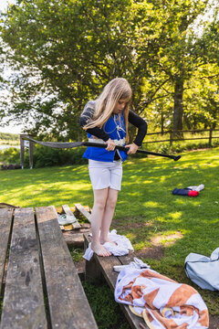 Young girl in life jacket assembling SUP paddle on bench
