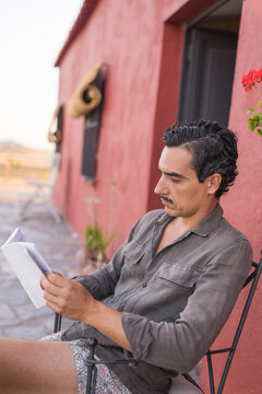 Man reading on patio at country house during summer vacation