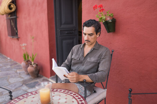 Man reading on patio at country house during summer vacation